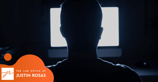 man sitting in front of a computer screen, facing away from the camera