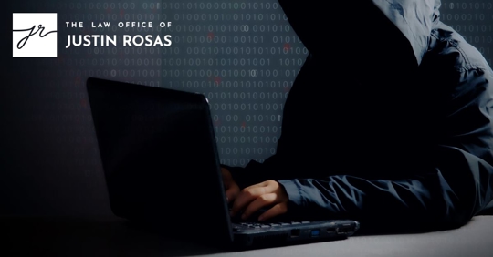 man with hood up typing on dark computer with 1's and 0's in the background